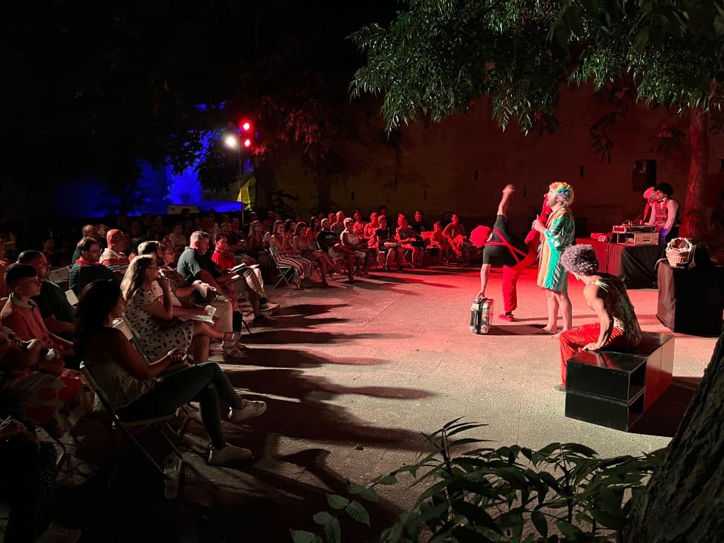 Outdoor night performance with colourful costumes and a seated audience